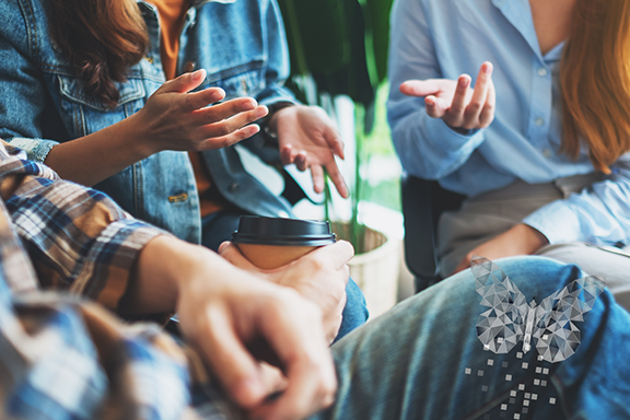 photo of people talking and sharing coffee. it is focused on their hands and their faces aren't showing